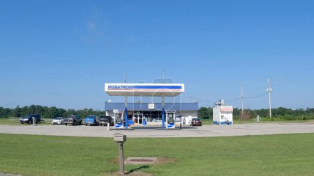 Foto de Statesboro, Ga USA - 08 09 23: POV Street pan Marathon gasolinera cielo azul claro tráfico pasando camión semirremolque y compartir paseo - Imagen libre de derechos