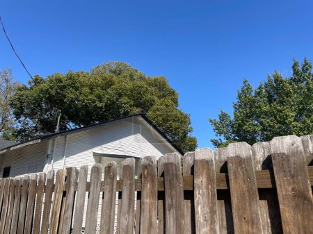 Brown wooden fence shadow box style blue sky summer background roof top