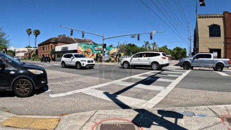 Foto de Lakeland, Fla USA - 03 16 24: Coches pasando el tráfico en una intersección de 4 vías cielo azul claro en Florida Ave - Imagen libre de derechos