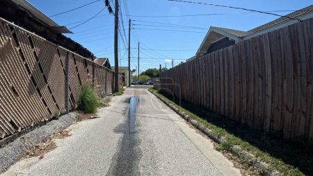 Téléchargez les photos : Lakeland, Fla États-Unis - 03 16 24 : Route de ruelle derrière les magasins et les bâtiments clôture en bois - en image libre de droit