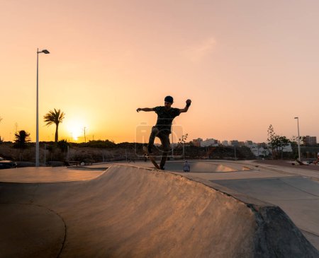 Photo for Young man skates in a skate park at sunset - Royalty Free Image