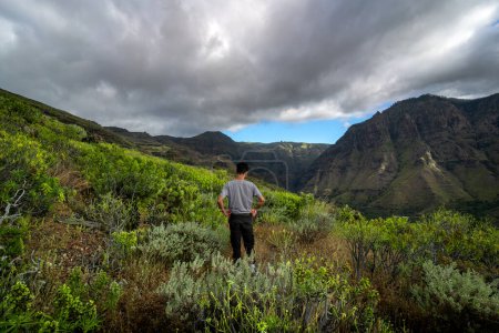 Téléchargez les photos : Le jeune homme contemple le paysage. La vallée d'Agaete. Gran Canaria. Pays-Bas - en image libre de droit