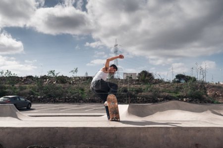 young man skates over the edge of a ramp in a skate park
