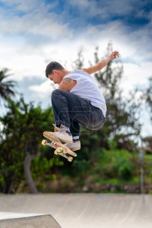 Junger Mann springt mit seinem Skateboard über eine Rampe