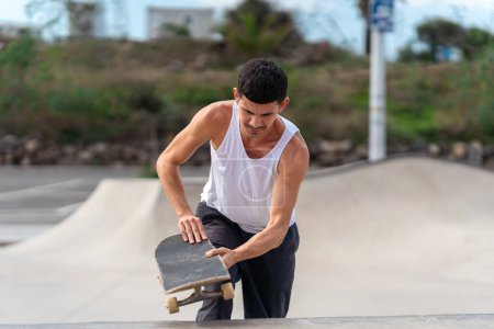 Foto de Hombre joven con patines de camiseta blanca en un parque de skate - Imagen libre de derechos