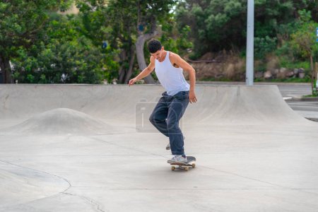 Foto de Hombre joven con patines de camiseta blanca en un parque de skate - Imagen libre de derechos