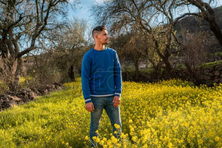 young man in a field of yellow wildflowers at sunset