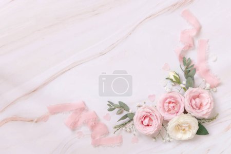 Photo for Pink and cream roses and silk ribbons on white marble top view. Romantic flat lay with pastel flowers. Wedding, Valentines, Spring or Mothers day concept - Royalty Free Image