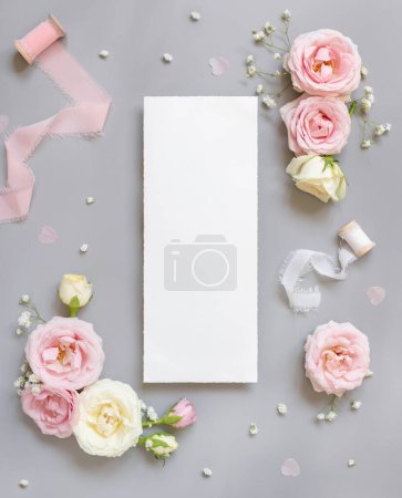 Téléchargez les photos : Menu Paper card between light pink roses and silk ribbons on grey top view,  wedding mockup. Romantic scene with blank vertical card and pastel flowers flat lay.. Valentines, Spring or Mothers day concept - en image libre de droit