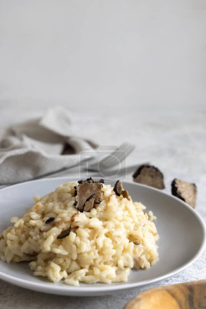 Téléchargez les photos : Risotto with wild porcini mushrooms and black truffles from Italy served in a plate close up on white table, copy space. Eating Italian gourmet cousine - en image libre de droit