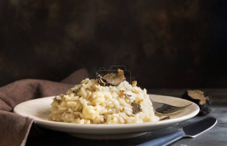 Risotto aux cèpes sauvages et truffes noires d'Italie servi dans une assiette près de la table grise, espace de copie. Manger de la cousine gastronomique italienne