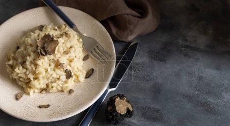 Photo for Risotto with wild porcini mushrooms and black truffles from Italy served in a plate close up on grey table, copy space. Eating Italian gourmet cousine - Royalty Free Image