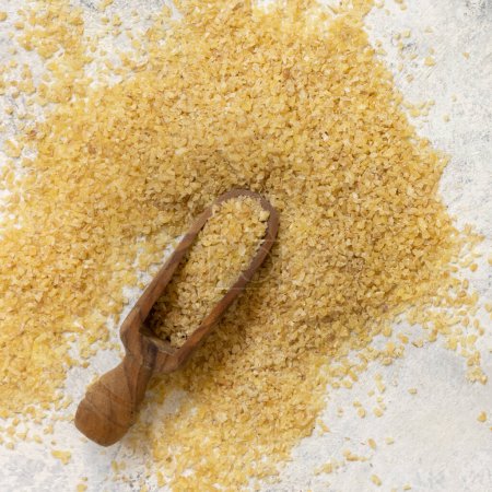 Photo for Wooden scoop of Dry uncooked bulgur wheat grain top view. Vegetarian and Vegan, Mediterranean and Middle Eastern cuisine. Healthy lifestyle - Royalty Free Image