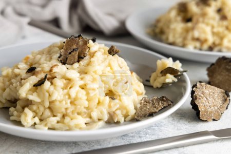 Photo for Risotto with wild porcini mushrooms and black truffles from Italy served in a plate close up on white table. Eating Italian gourmet cousine - Royalty Free Image