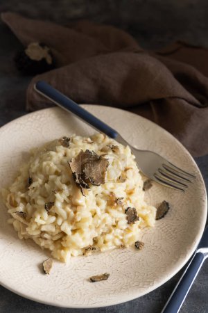Téléchargez les photos : Risotto with wild porcini mushrooms and black truffles from Italy served in a plate close up on grey table, copy space. Eating Italian gourmet cousine - en image libre de droit