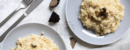 Foto de Risotto with wild porcini mushrooms and black truffles from Italy served in a plate top view on white table, copy space. Eating Italian gourmet cousine - Imagen libre de derechos