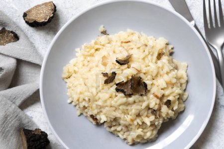 Téléchargez les photos : Risotto aux cèpes sauvages et truffes noires d'Italie servi dans une assiette vue sur la table blanche. Manger de la cousine gastronomique italienne - en image libre de droit