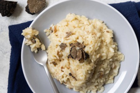 Photo for Risotto with wild porcini mushrooms and black truffles from Italy served in a plate top view on a table. Eating Italian gourmet cousine - Royalty Free Image