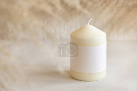 Photo for Candle with blank paper label on white table with dried pampas grass, Close up, copy space. Minimal brand packaging mock up. Home decoration, minimal interior, Bohemian or scandinavian styl - Royalty Free Image