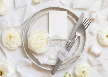 Photo for Wedding table setting with a small card near cream roses and white silk ribbons top view, mockup. Romantic scene with vertical table place card and pastel flowers. Valentines, Spring or Mothers day concept - Royalty Free Image