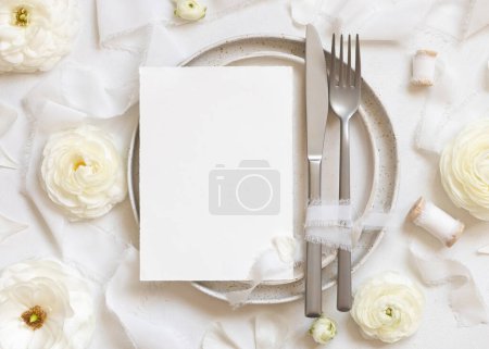Foto de Ajuste de mesa de boda con tarjeta cerca de rosas crema y cintas de seda blanca vista superior, maqueta. Escena romántica con carta de menú vertical y flores pastel. Concepto de San Valentín, Primavera o Madres - Imagen libre de derechos