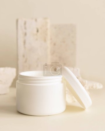 Photo for Opened white cream jar with a lid near biege travertine stones, close up, mockup. Skincare beauty product. Eco friendly cosmetics - Royalty Free Image