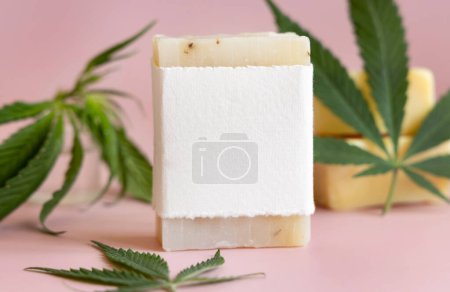 Photo for Craft soap bar with blank label near green cannabis sativa leaves on pink close up. Cosmetic Mockup, Copy space. Organic skincare beauty product. Eco friendly CBD soa - Royalty Free Image