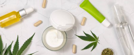 Photo for Cream bottles, jars and tubes with blank label and capsules near green cannabis sativa leaves on a marble table top view. Mockup, Copy space. Organic skincare beauty products. CBD Cosmetic - Royalty Free Image