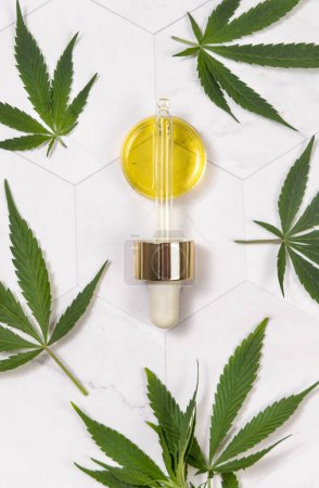 Photo for Pipette with CBD oil near green cannabis leaves close up on white marble top view. Organic health care product to relax and sleep. Alternative healthcare concep - Royalty Free Image