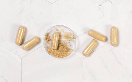 Photo for Dietary supplement capsules on white marble table top view. One capsule opened to show beige powder in a jar. Preventive medicine and healthcare, taking vitamins. Pharmaceutical product - Royalty Free Image