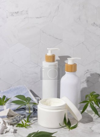 Photo for Opened cream jar with blank lid near green cannabis leaves on wooden tray in bathroom near other bottles, close up, mockup. Organic skincare beauty products, natural CBD cosmetic - Royalty Free Image