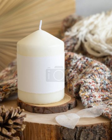 Photo for Candles with blank paper label near pine cones and sweater, Close up, copy space. Boho packaging mock up. Home decorations, Bohemian or scandinavian styl - Royalty Free Image