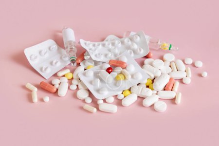 Foto de Mezcla de cápsulas médicas y pastillas con ampollas en la vista superior rosa claro. Tratamiento médico. Tomar suplementos dietéticos y vitaminas. Productos farmacéuticos surtidos - Imagen libre de derechos
