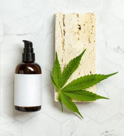 Photo for One pump Cosmetic bottle with blank label and green cannabis leaves on beige stone top view. Organic Eco friendly CBD cosmetics. Alternative lifestyl - Royalty Free Image