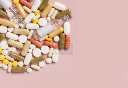 Photo for Mix of medical capsules and pills on light pink top view, copy space. Medicinal treatment. Taking dietary supplements and vitamins. Assorted pharmaceutical products - Royalty Free Image