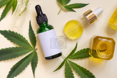 Photo for Pipette with CBD oil and  dropper bottle with blank label near green cannabis leaves on beige top view. Organic skincare beauty products, natural alternative cosmetic - Royalty Free Image