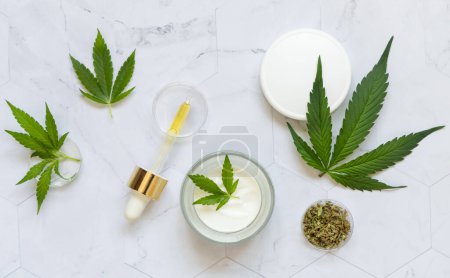 Photo for Pipette, cream jar and infusion tea near green cannabis leaves top view on marble. Organic healthcare product. Eco friendly CBD oil to relax and sleep. Alternative healthcare and bodycare concep - Royalty Free Image