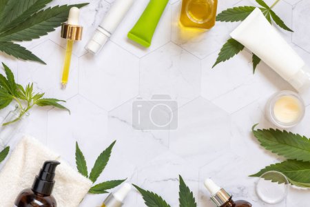 Photo for Cosmetic bottels, jars and tubes, pipette with CBD oil and green cannabis sativa leaves on a marble table top view, copy space. Organic skincare and healthcare products. - Royalty Free Image