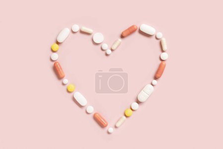 Photo for Heart shape  made of colorful drug pills and capsules on light pink, top view. Pharmaceutical and cardiology concept, treatment of heart diseases. - Royalty Free Image