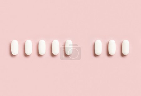 Photo for Mix of medical pills with one empty place in a line on light pink top view. Preventive medicine and healthcare, dietary supplements and vitamins.  Assorted pharmaceutical medicine capsules - Royalty Free Image
