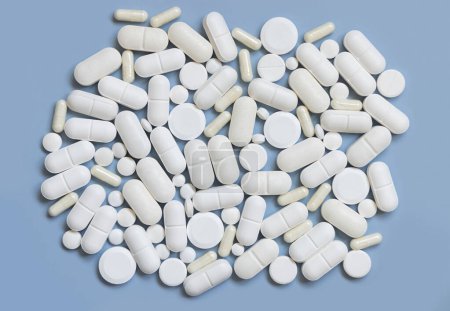 Foto de Mezcla de cápsulas médicas blancas y pastillas en la vista superior azul claro. Tratamiento médico. Tomar suplementos dietéticos y vitaminas. Productos farmacéuticos surtidos - Imagen libre de derechos