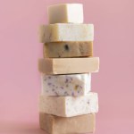 Tower stack of beige handmade soap bars on light pink close up. Natural herbal products for Spa and skin care