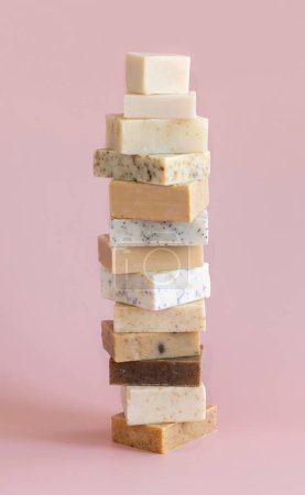 Foto de Torre pila de barras de jabón hechas a mano beige en rosa claro de cerca. Productos herbarios naturales para Spa y cuidado de la piel - Imagen libre de derechos