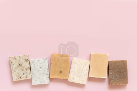 Photo for Beige and brown handmade soap bars in a line on light pink top view, copy space. Natural herbal products for Spa and skin care. Using organic handmade skincare products in everyday routine - Royalty Free Image