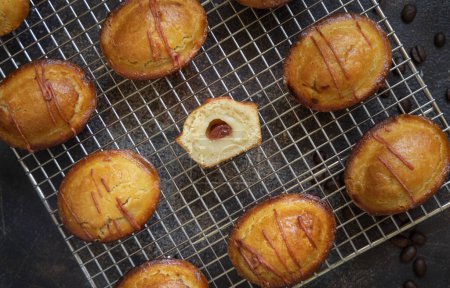 Photo for Pasticciotto leccese pastry filled with egg custard cream and sour cherry jam on a cooling backing rack on a dark table, top view.  Typical apulian breakfast - Royalty Free Image