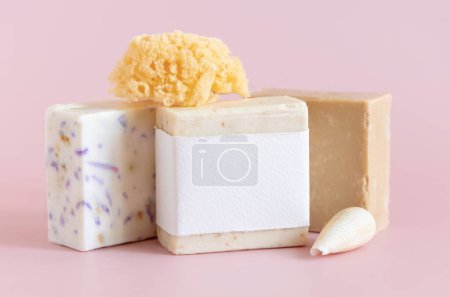 Photo for Beige handmade soap bars with blank label, natural sponge and seashell on light pink close up, packaging mockup, copy space. Herbal products for face and body care - Royalty Free Image