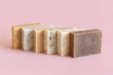Photo for Beige and brown soap bars in a line on light pink close up, copy space. Natural herbal products for Spa and skin care. Using organic handmade skincare products in everyday routine - Royalty Free Image