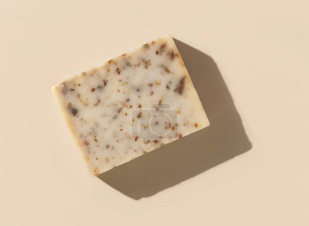 Photo for Natural herbal beige soap bar on light beige top view, hard shadows. Hygiene products for Spa and skin care. Using organic handmade soap for everyday bathroom routine - Royalty Free Image