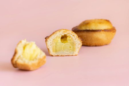 Photo for Pasticciotto leccese pastry filled with egg custard cream, typical sweet from Lecce, Italy. Half of baked pasticiotto on a pink, apulian breakfast, close up - Royalty Free Image