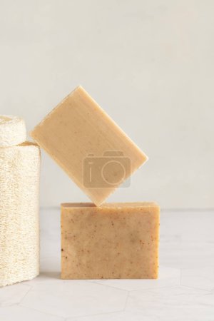 Téléchargez les photos : Barres de savon faites à la main beige sur table en marbre près de l'éponge loofah naturelle fermer, copier l'espace. Produits naturels à base de plantes pour l'hygiène quotidienne du visage et du corps - en image libre de droit